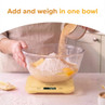 Yellow digital kitchen scale weighing ingredients in a clear mixing bowl