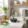 Salter black egg cooker with clear lid on kitchen worktop, eggs and herbs nearby
