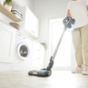 Cordless stick vacuum in use on light wood floor in modern laundry room