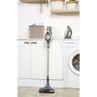 Cordless stick vacuum cleaner in gold and grey, upright in modern laundry room