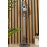 Cordless stick vacuum cleaner in gold and grey, upright against wooden wall panel