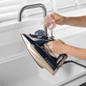 Filling water in a navy and gold steam iron at a kitchen sink
