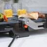 Close-up of electric grill cooking vegetables, sweetcorn, and meat in a kitchen setting