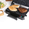 Contact grill cooking two chicken breasts and a steak on speckled grill plate