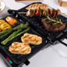 Countertop electric grill with steak, grilled vegetables and halloumi shown cooking