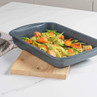 Blue speckled non-stick roasting tray shown with roasted vegetables, kitchen surface setting