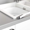 White handled crevice cleaning brush scrubbing around kitchen sink edge