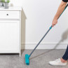 Person using a blue rubber broom to sweep grey carpet