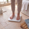 Person standing on white digital bathroom scale, display visible
