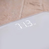 White digital bathroom scale with LED display showing 73.3 kilograms
