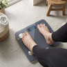 Person standing on grey digital bathroom scale, display shows 60.0 kg