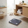 Grey digital bathroom scale with display, placed on tiled floor in modern bathroom