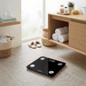 Black digital bathroom scale with silver sensors on tiled floor in modern bathroom