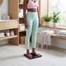 Person standing on bathroom smart scale, fitness attire, in modern bathroom setting