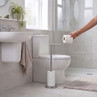 Stainless steel toilet roll holder stand with spare rolls, shown in a modern bathroom