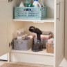 Black handheld clothes steamer on shelf with laundry sprays and folded towels