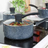 Grey speckled saucepan with glass lid on induction hob, food cooking inside