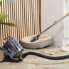 Cylinder vacuum cleaner in grey cleaning near pet bed, shown in home setting