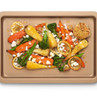 Gold non-stick oven tray with roasted root vegetables, lemon slices and crumbled cheese