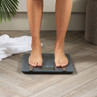 Person standing on black digital bathroom scale on wood floor