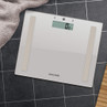 White digital bathroom scale with silver accents on black tiled floor