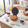 Red bubble waffle maker on kitchen counter with cooked bubble waffles inside