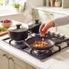 Black saucepan set on gas hob with frying pan