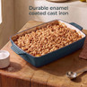 Rectangular blue enamel cast iron baking dish filled with crumble, shown on wooden table.