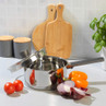 Stainless steel saucepan with black handle and lid, shown with fresh vegetables on worktop