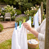 Person hanging white washing on outdoor clothesline in garden