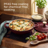 Deep red casserole dish with spinach and cheese bake, shown on induction hob