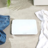 White digital bathroom scale on tiled floor with jeans and towel nearby