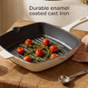 Cream enamelled cast iron grill pan with roasted tomatoes and herbs, shown on table.