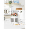 White and silver food processor with chopped vegetables inside, shown on a kitchen counter