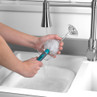 Hand washing a wine glass with a blue-handled brush under running tap water