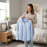 Light blue long-sleeve shirt on hanger held in a bedroom setting