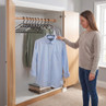 Woman holding light blue shirt on black clothes hanger in open wardrobe