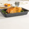 Grey speckled roasting tray with golden whole roast chicken and green vegetables