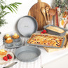 Grey non-stick baking tins with cakes and bread in kitchen setting