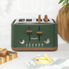 Green four-slice toaster with wood-effect accents and toast inside, shown on kitchen counter