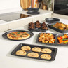 Set of grey speckled non-stick baking trays on kitchen counter with cooked food