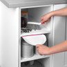 Hand using pink and white dustpan and brush set to sweep up coffee beans from kitchen shelf