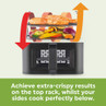 Black air fryer with salmon and vegetables showing separate racks for crisping and sides