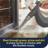 Steam cleaner nozzle removing oven grease and grime, demonstrates flexible cleaning tool.