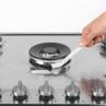 Hand cleaning stainless steel gas hob with brush and cleaning foam