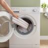 Person placing grey striped cleaning pad into washing machine