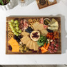 Sharing platter of assorted cheeses, crackers, fruit and cured meats on a wooden board
