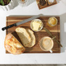 Breakfast scene with sliced sourdough bread, butter, honey, and a cup of coffee on a wooden board