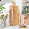 Large natural wood serving board with handle on kitchen worktop