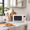 Cream microwave oven on kitchen counter with digital display